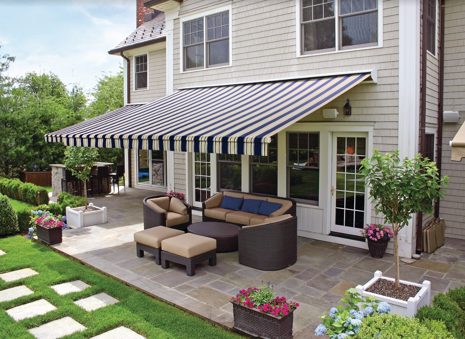 A motorized retractable awning with navy blue and cream stripes extends over a patio.