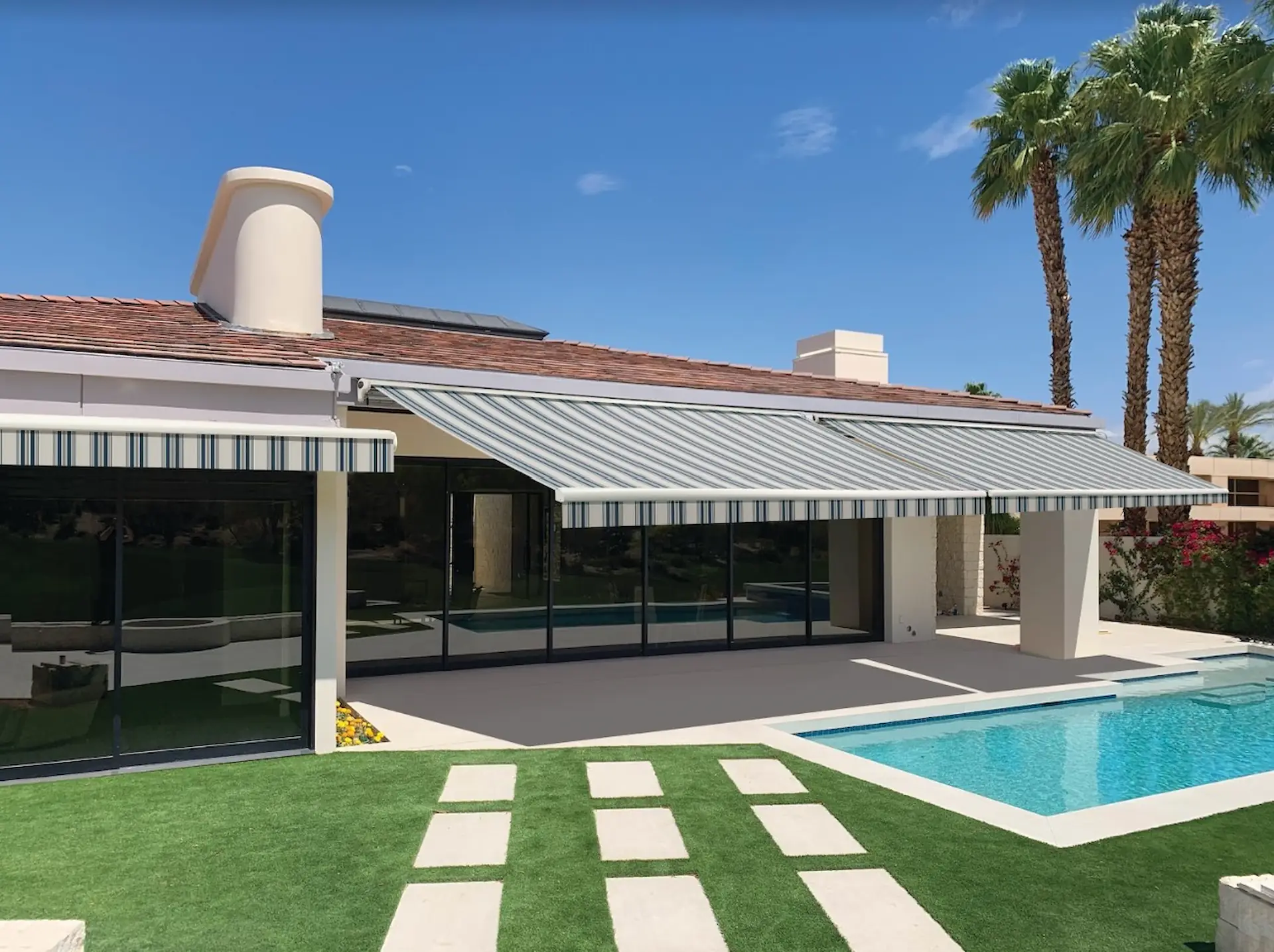 Exterior shot of a ranch home with a striped retractable awning extended over the patio. Striped patterns like these are a popular look for a quality awning.