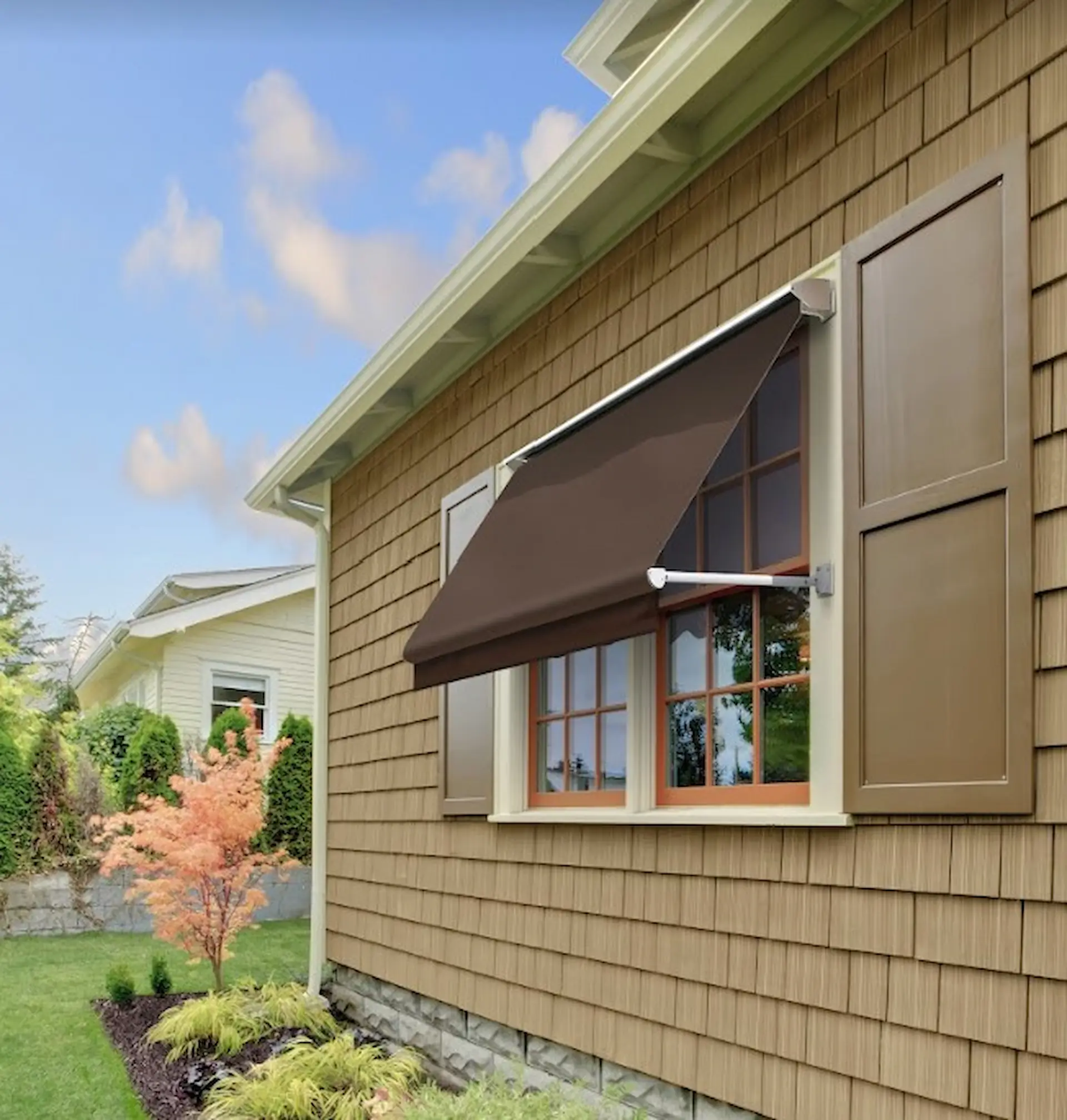 Medium shot of a window shielded by a brown retractable window awning. Solid colors are one of the popular window awning ideas for 2023.