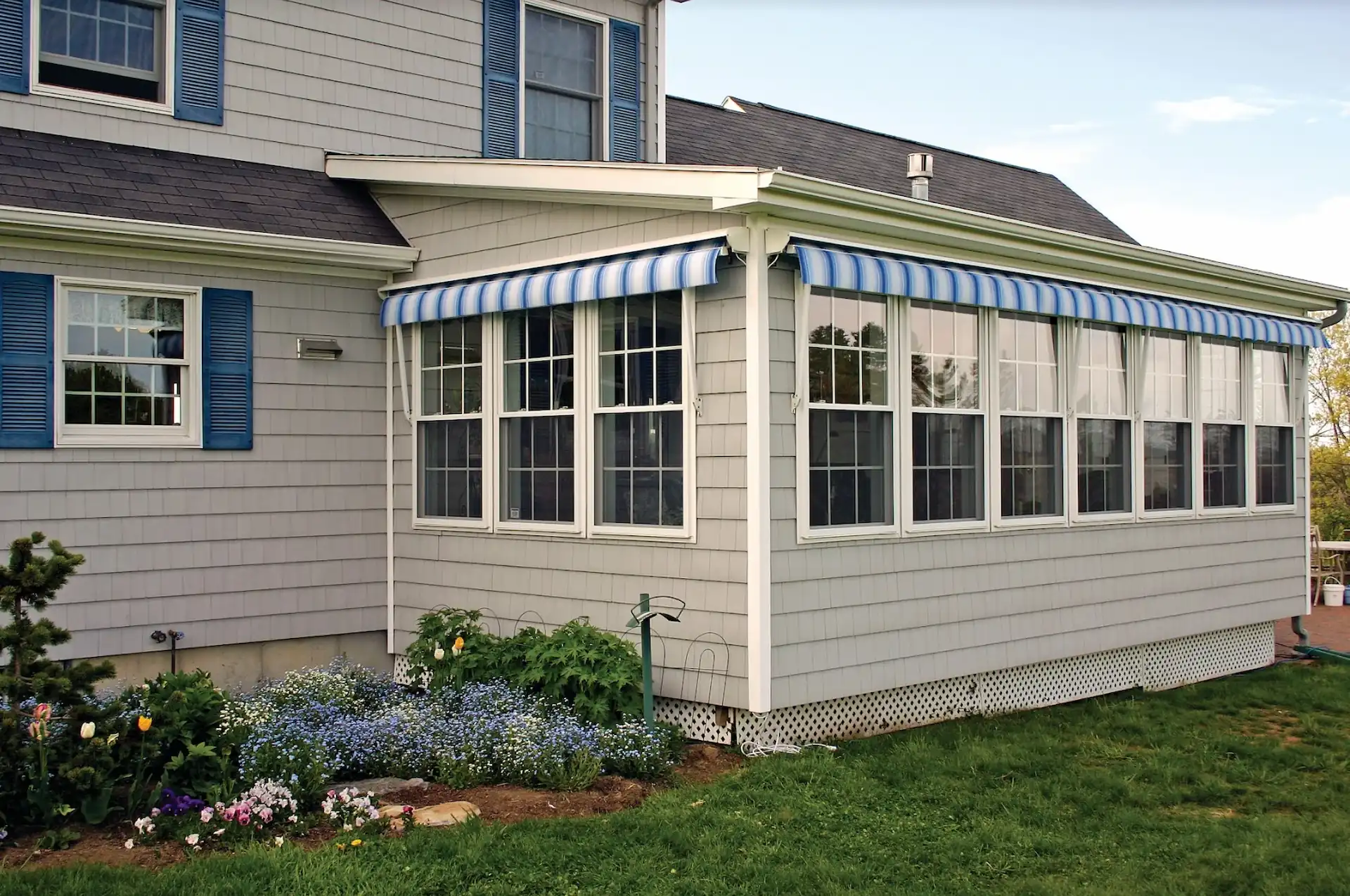 Exterior shot of a sun room lined with fabric awnings in their retracted position. Knowing when your retractable awnings should be in their closed position is crucical to maintaining their longevity.