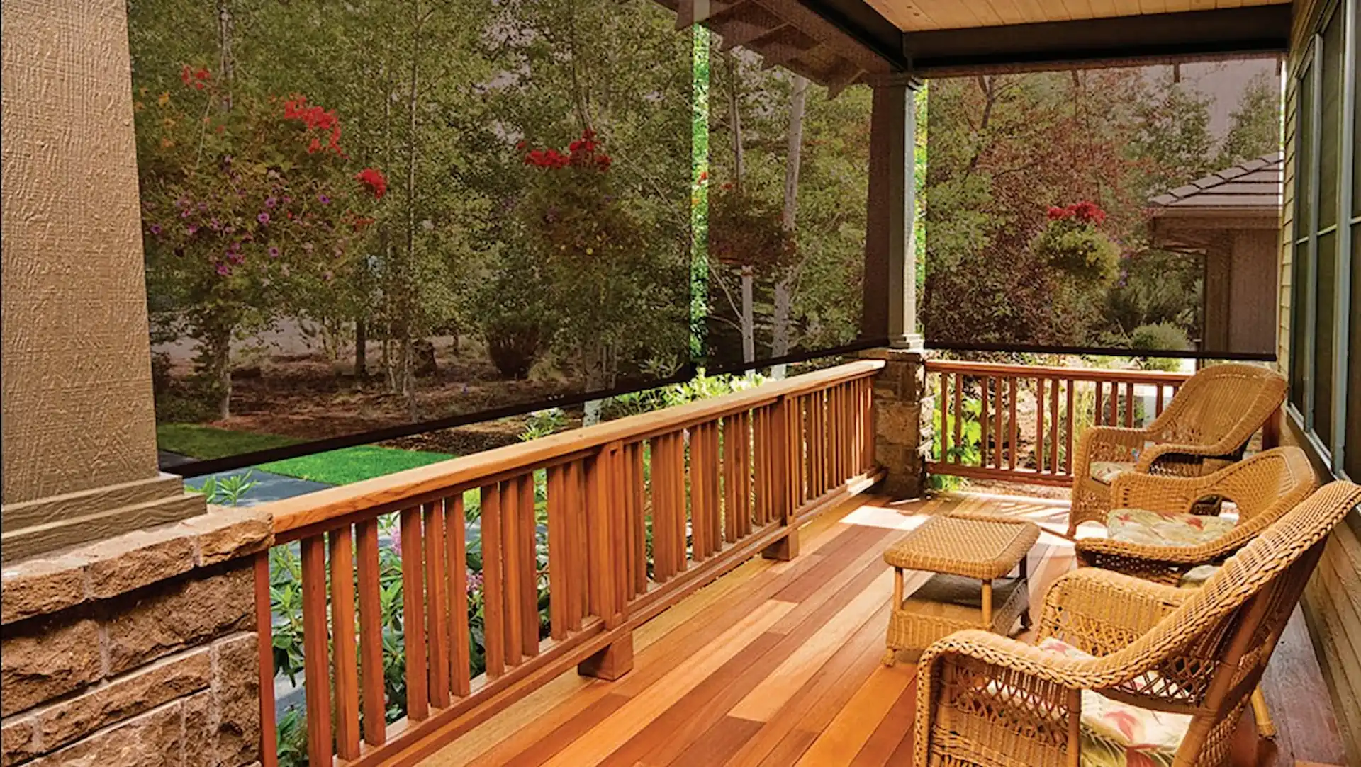 Exterior shot of a porch with wooden floors and railings. Non-zip shade screens are hanging from the porch roof to help shield the porch area from sun glare.