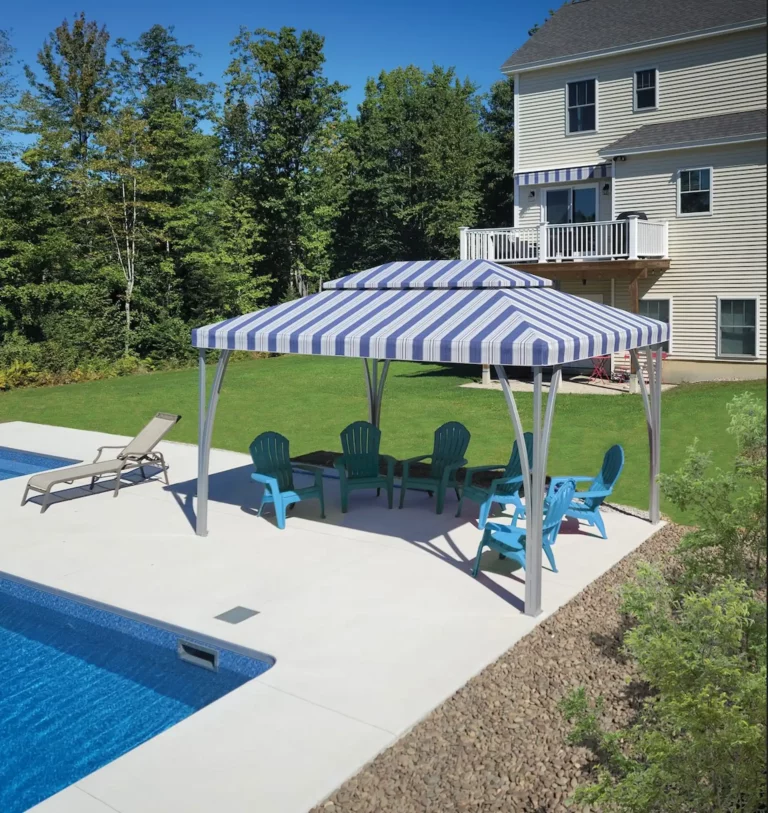 A striped open air cabana with deck chairs underneath it sits on a pool deck in the sunshine.