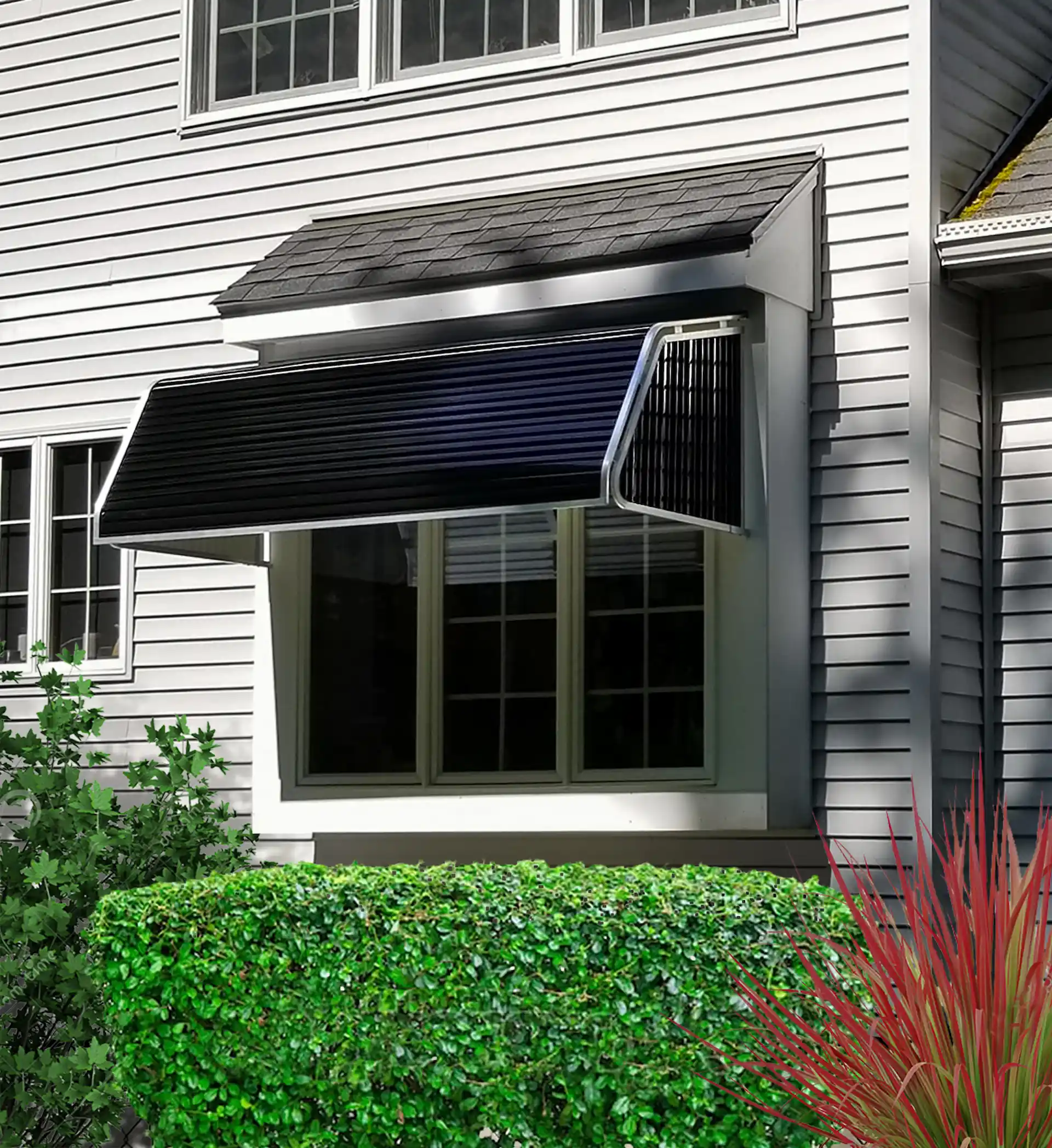 Medium shot of a black fixed awning on the side of a white house. Window awnings like this require specialized installation knowledge when deciding to move them from one home to another.
