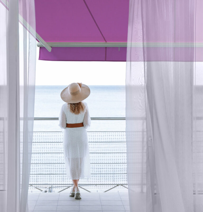 A woman stands under a stunning purple window awning.