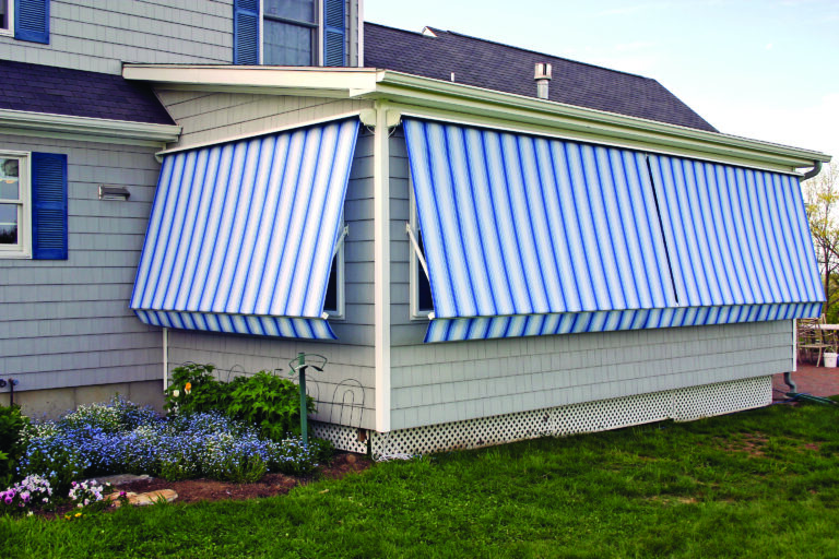 Blue and white stripped Robusta window awnings covering the exterior windows on a house.